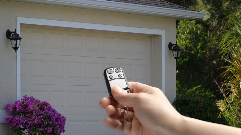 Hand holding remote opening garage door