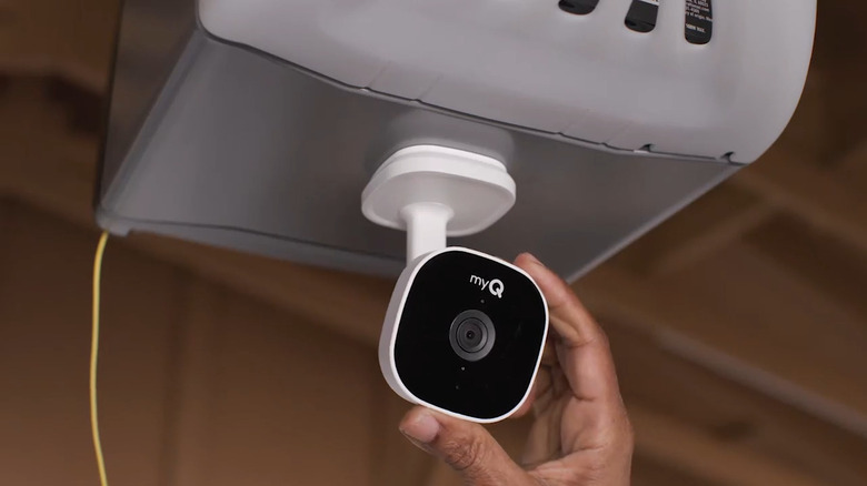 Hand adjusting myQ Smart Garage Security Camera installed in garage