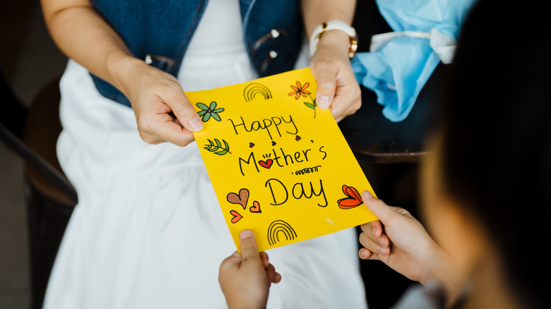 A mother receiving a Mother's Day card from her child.