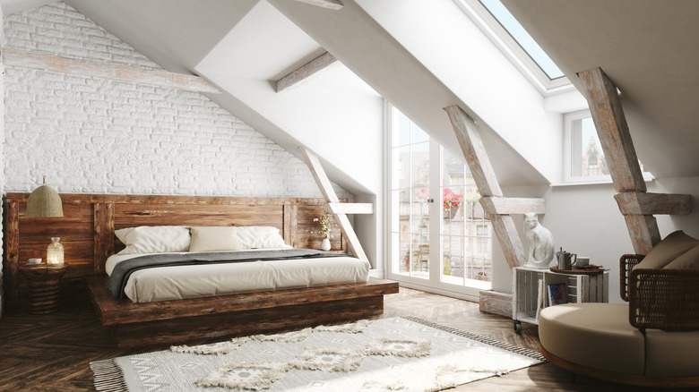 A large white bedroom with a king sized bed, a sun roof, and exterior doors that bring in a lot of natural light