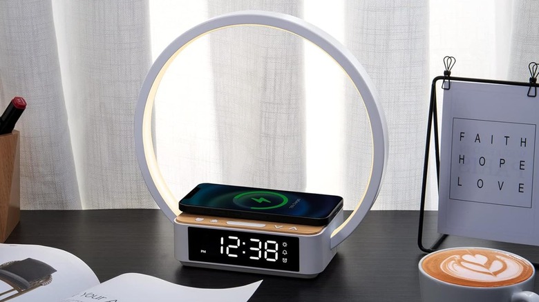 A Wilit Bedside Lamp with Alarm Clock and Wireless Charger sitting on a desk next to a small desk sign displaying a positive affirmation