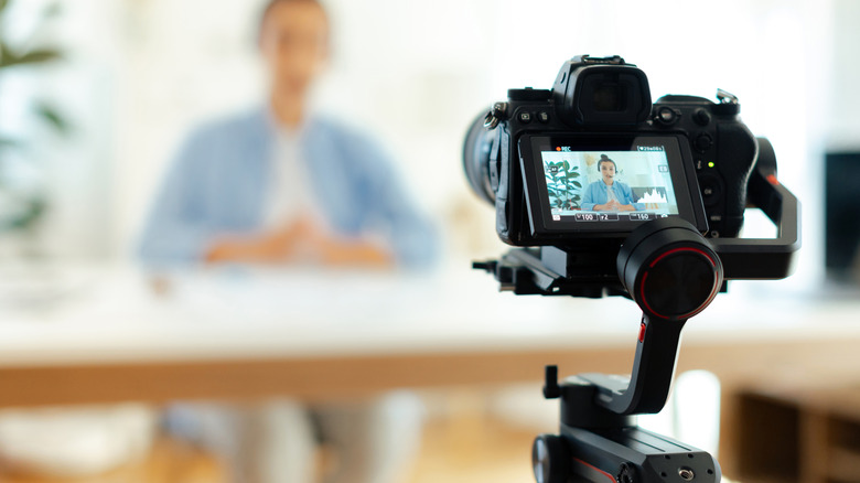 A digital camera recording a person who's blurred in the background.