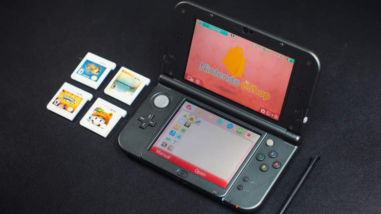 Nintendo 3DS on a black table next to game cartridges and a stylus