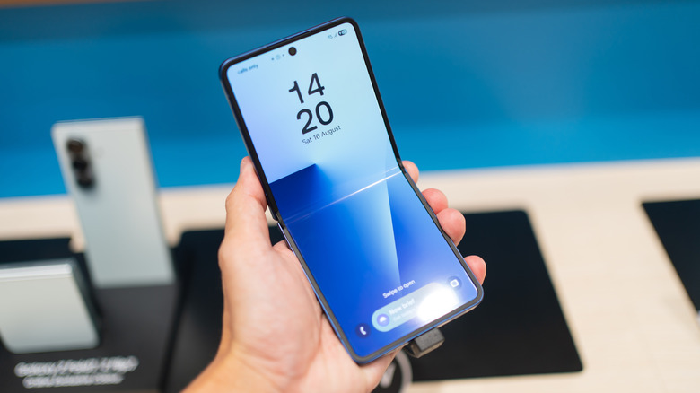 a person holding a Samsung Galaxy Z Flip 7 while showing the lock screen