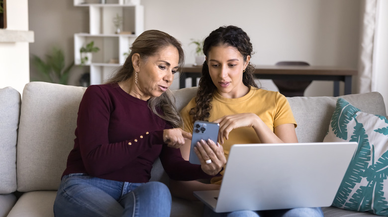 Two women pointing and looking at a phone screen