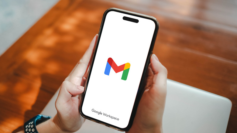 Person holding an iPhone with Gmail loading screen displayed