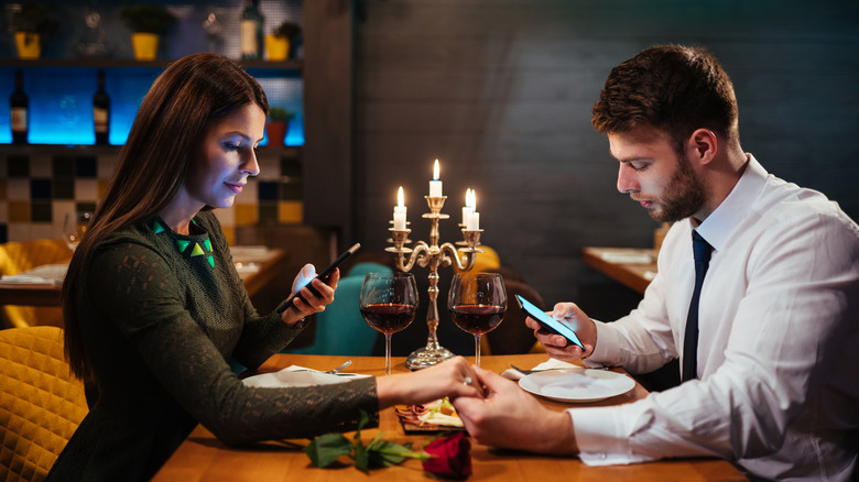 couple on phones at upscale restaurant