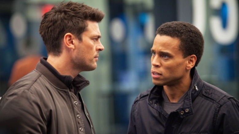 Detective John Kennex (Karl Urban) and Dorian (Michael Ealy) talking on a street.