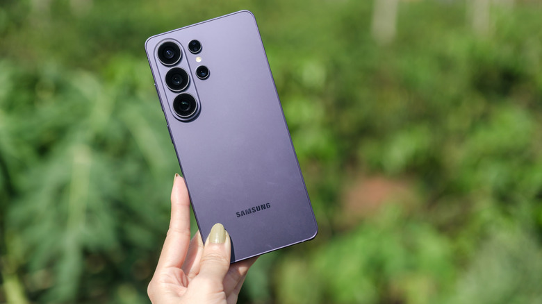 Single hand holding S26 Ultra showing rear of phone with camera bump and logo