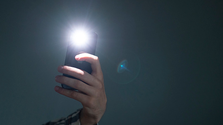 Phone held in hand with flash on for flashlight function