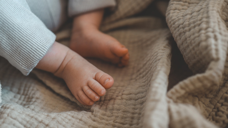 The feet of a newborn in a cradle.