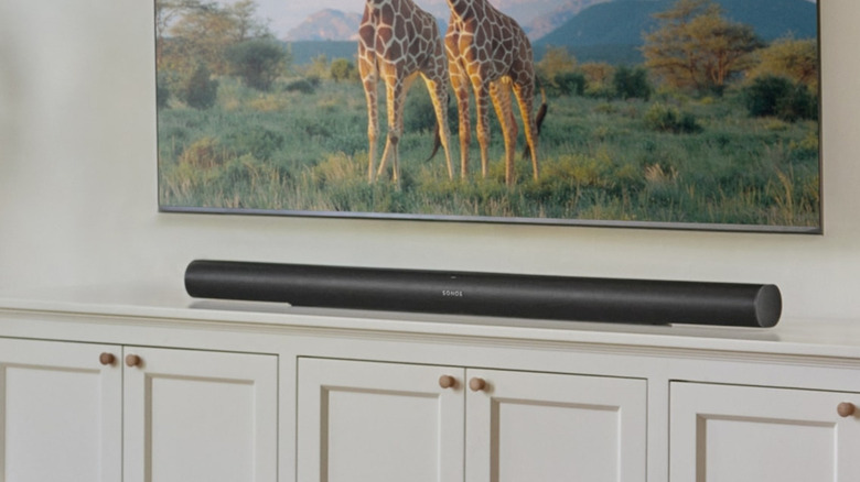 The Sonos Arc Ultra soundbar sitting on a console underneath a mounted flatscreen TV
