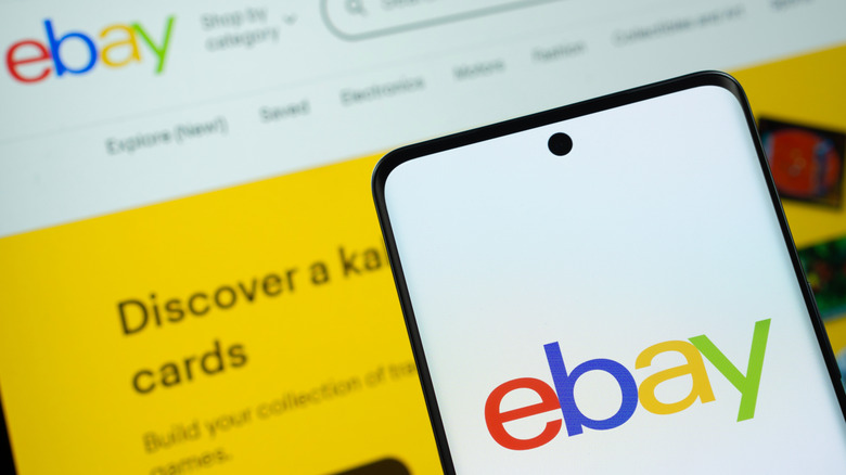 smartphone showing ebay logo and ebay website visible in the background