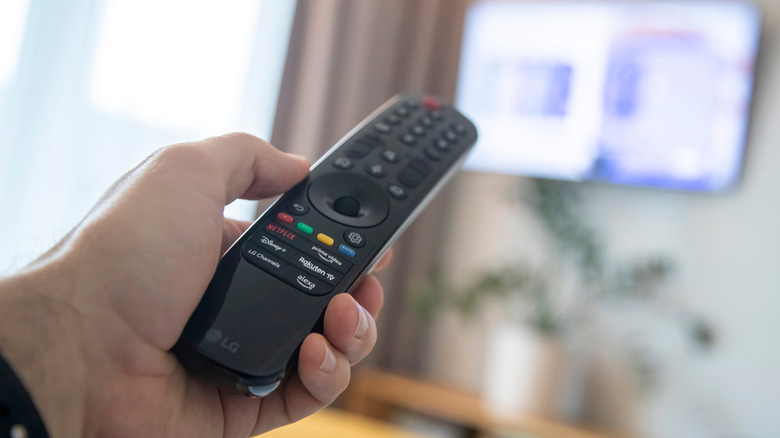 Person pointing remote at smart tv