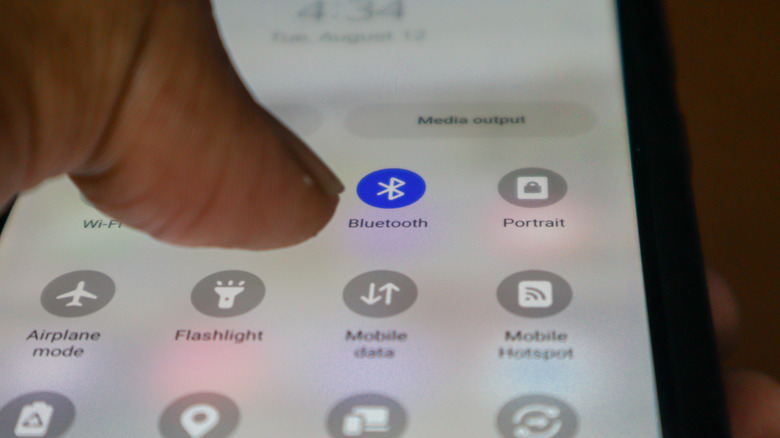 A person enabling the Bluetooth setting on a smartphone.