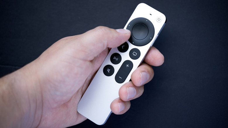 A person holding the 2nd generation Siri remote.