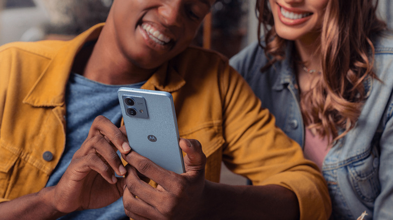 Two people looking at the screen of Motorola phone