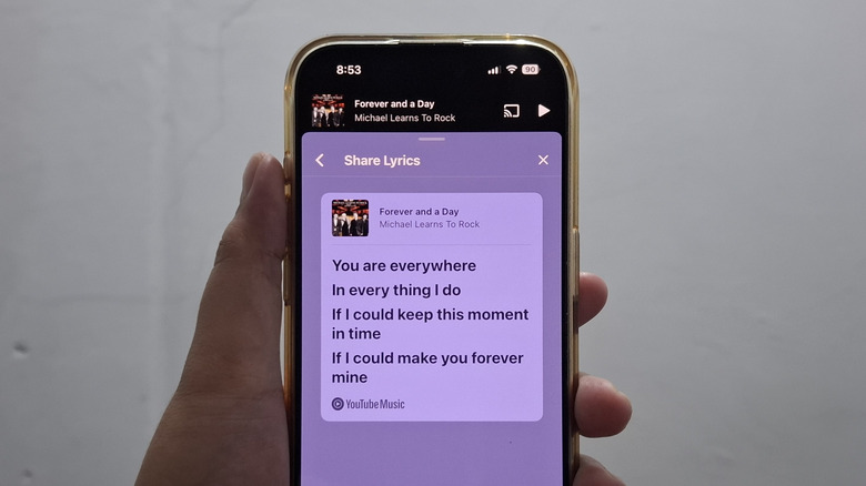Hand holding phone showing lyric image on YouTube Music
