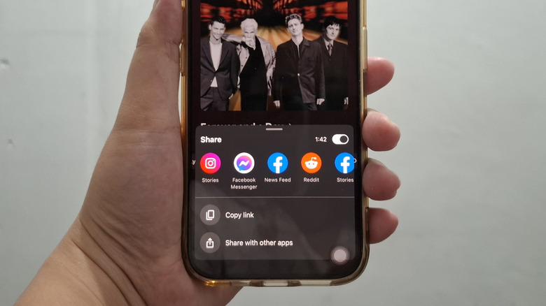 Hand holding phone showing timestamped song on YouTube Music share panel