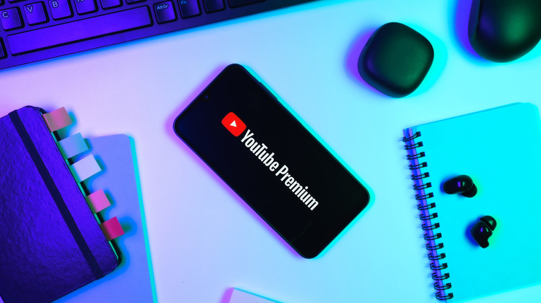 Phone on work station table with other gadgets showing YouTube Premium logo