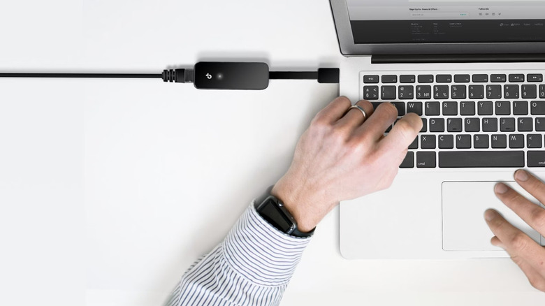 TP-Link ethernet adapter connected to laptop with hands on the keyboard
