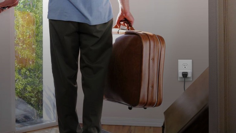 Kasa Smart Plug HS103P2 plugged into the wall with connected device while homeowner is leaving the house