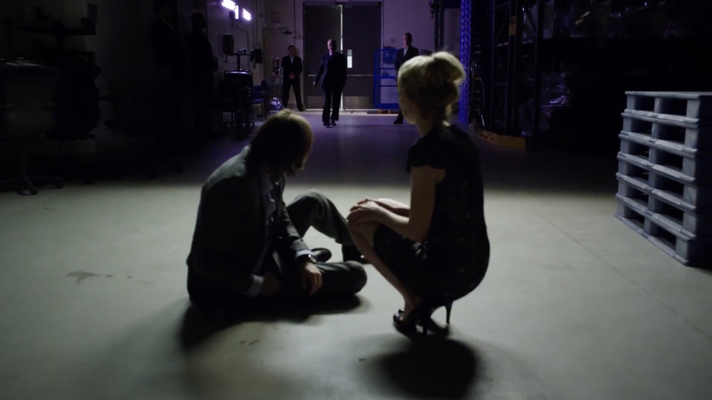 Two people low on the floor await a man who is approaching