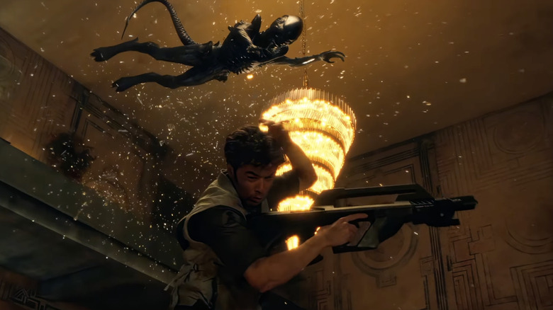 An alien flies through the air while a character from "Alien: Earth" takes cover