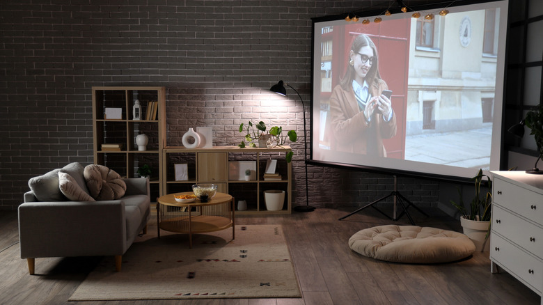 A sofa and table in front of a projector and home theater setup