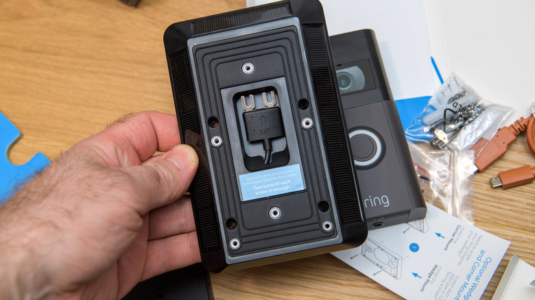 A person holding a solar charging kit for a Ring doorbell.