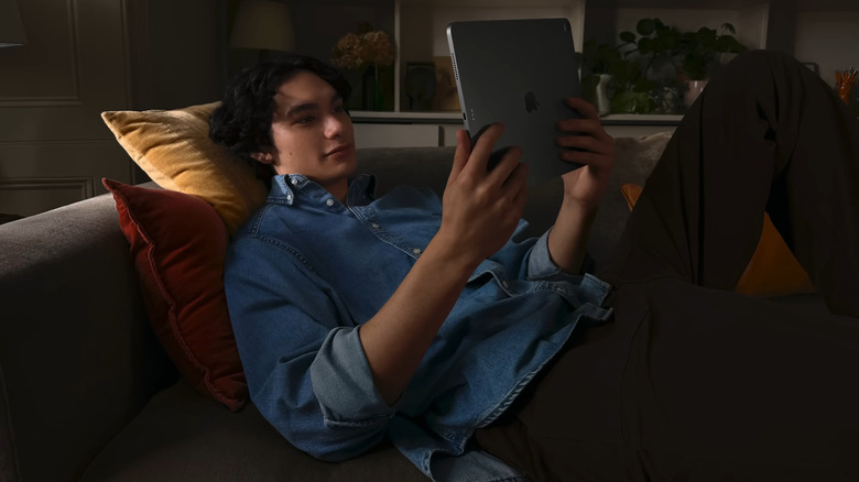 Man holding iPad while lounging on the couch