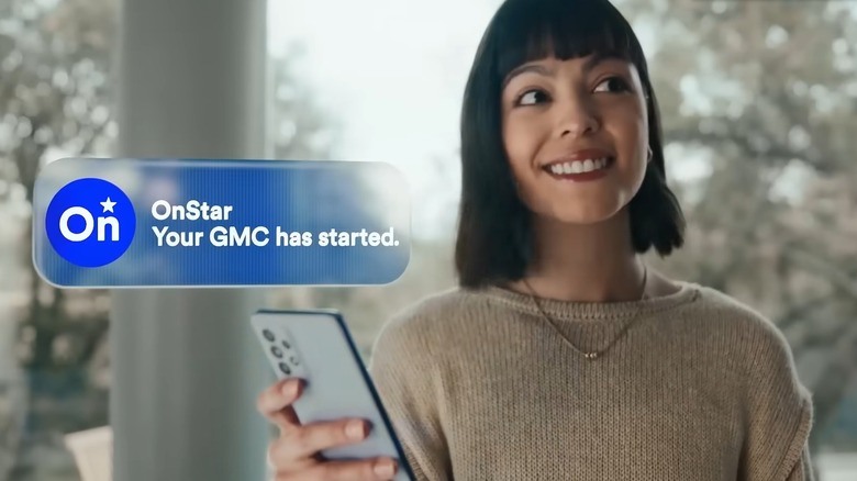 A smiling lady in her kitchen with a smartphone in her hand as a graphic says "Your GMC has started."