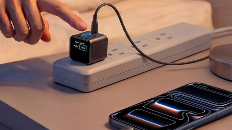 The Anker Nano Smart Display Charger plugged into a power strip atop a nightstand.
