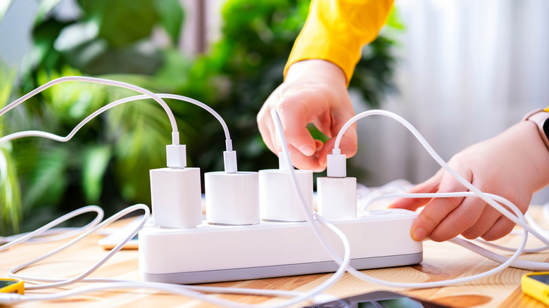 person plugging multiple chargers into an extension cord