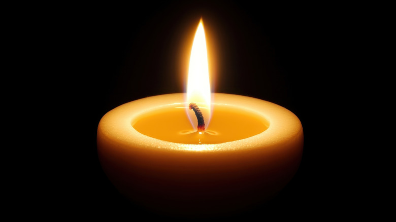 A single, lit candle against black background