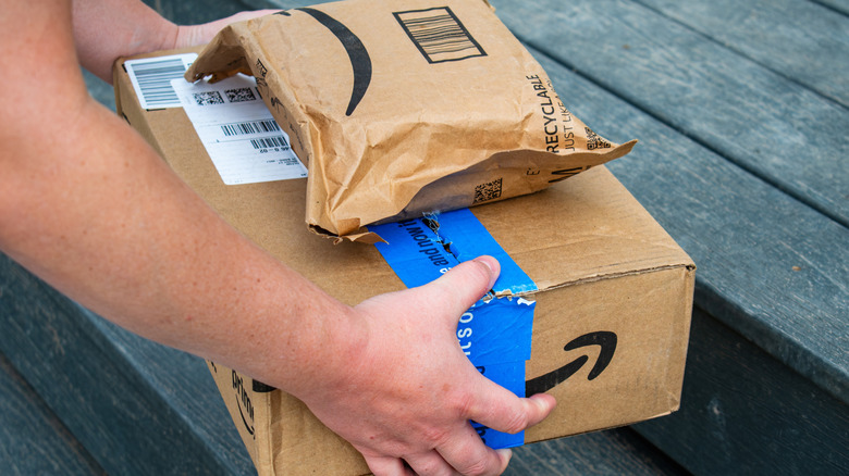 A person placing Amazon packages in front of a doorstep
