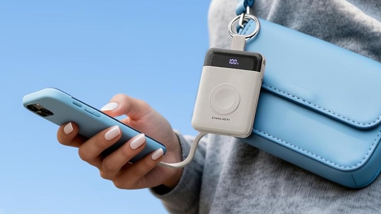A person using a Chaligti Portable Charger clipped to a bag.