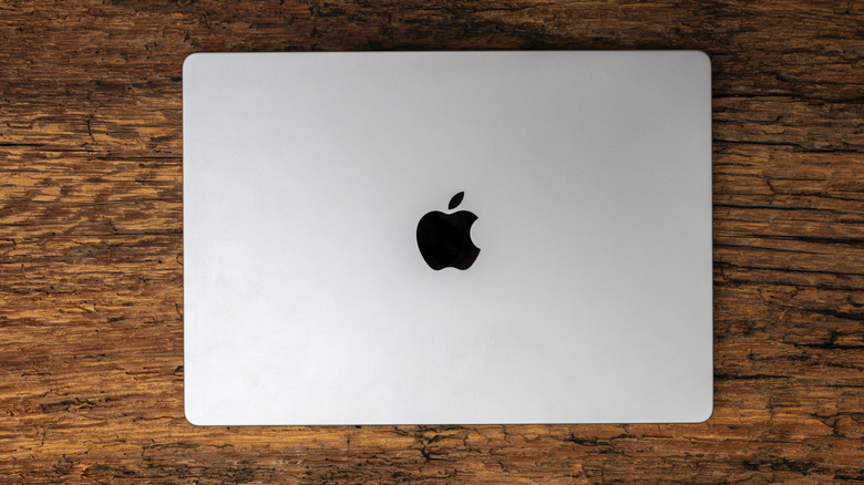 A birds-eye view of a closed Macbook Pro on a wooden table.