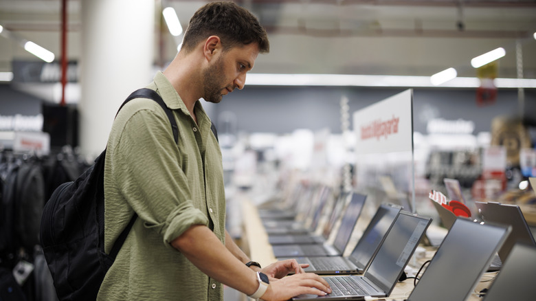 A man in an electronics store considering a laptop display