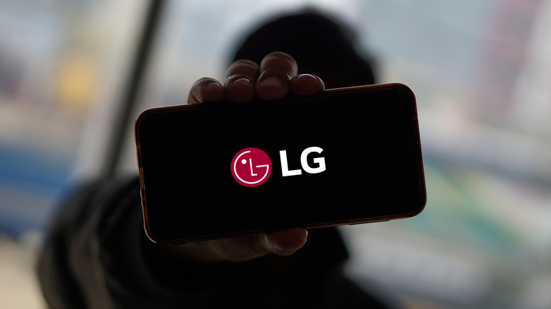 Person holding a smartphone displaying the LG logo.