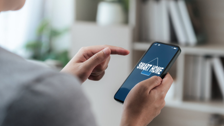 A man holding a phone with the word smart home on the screen.