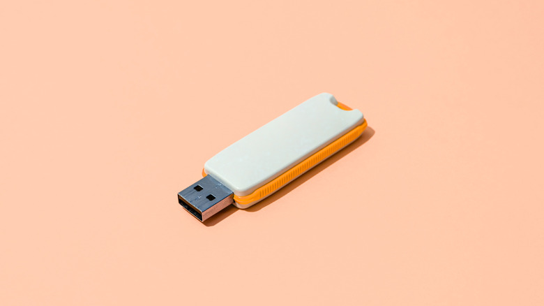 High-angle view of white USB pen drive on orange background.