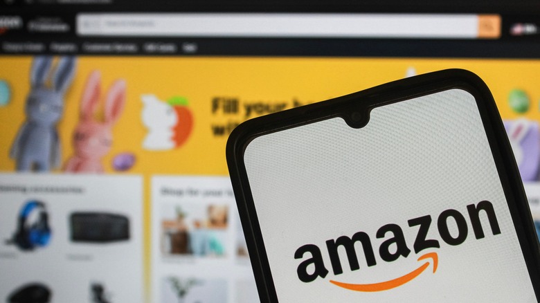 amazon logo on a smartphone with the website open in the background