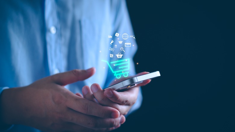 hands holding a phone with a digital shopping cart icon imposed upon it