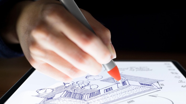 A hand holding a Logitech pencil while drawing on an iPad