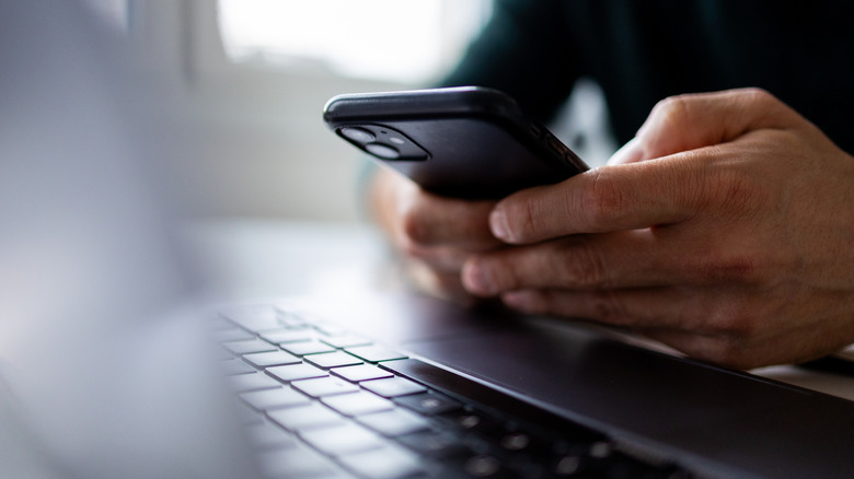 A person using an iPhone and a MacBook