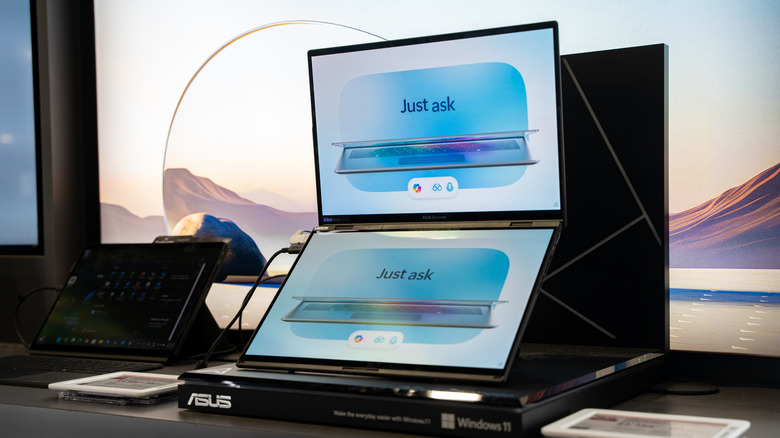 An open Asus ZenBook Duo laptop with two screens that read "Just Ask" with laptop graphics