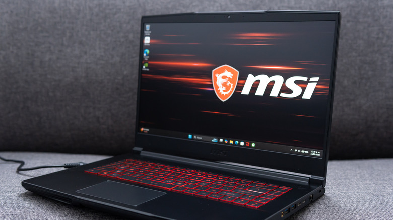 MSI GF65 gaming laptop open and running, with the MSI logo as background