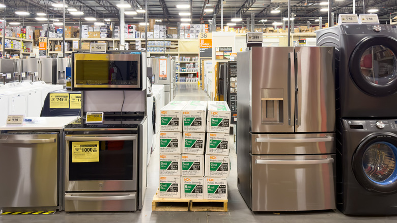 GE Appliances-brand products, including a dishwasher, an oven, a fridge, and more, on display in a warehouse-style store.