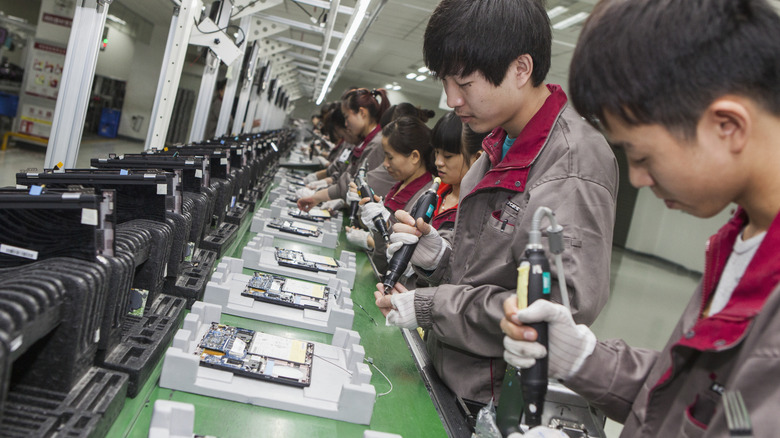 Workers using tools to build components in a Chinese factory.